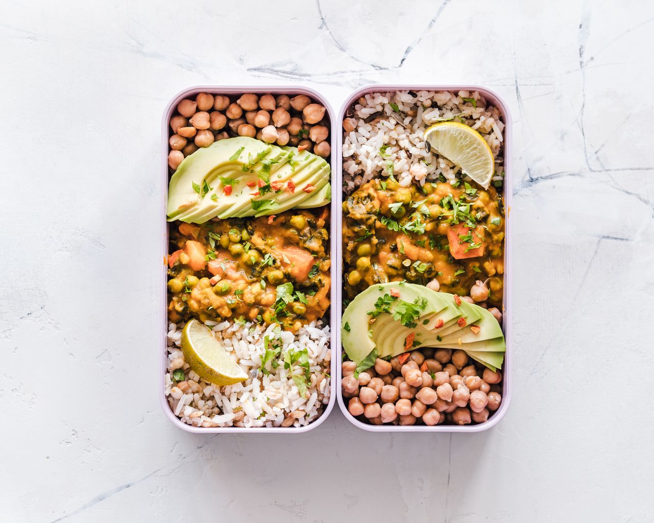 Home Delicious vegan lunchboxes featuring chickpeas, rice, avocado, and curry on a white background.