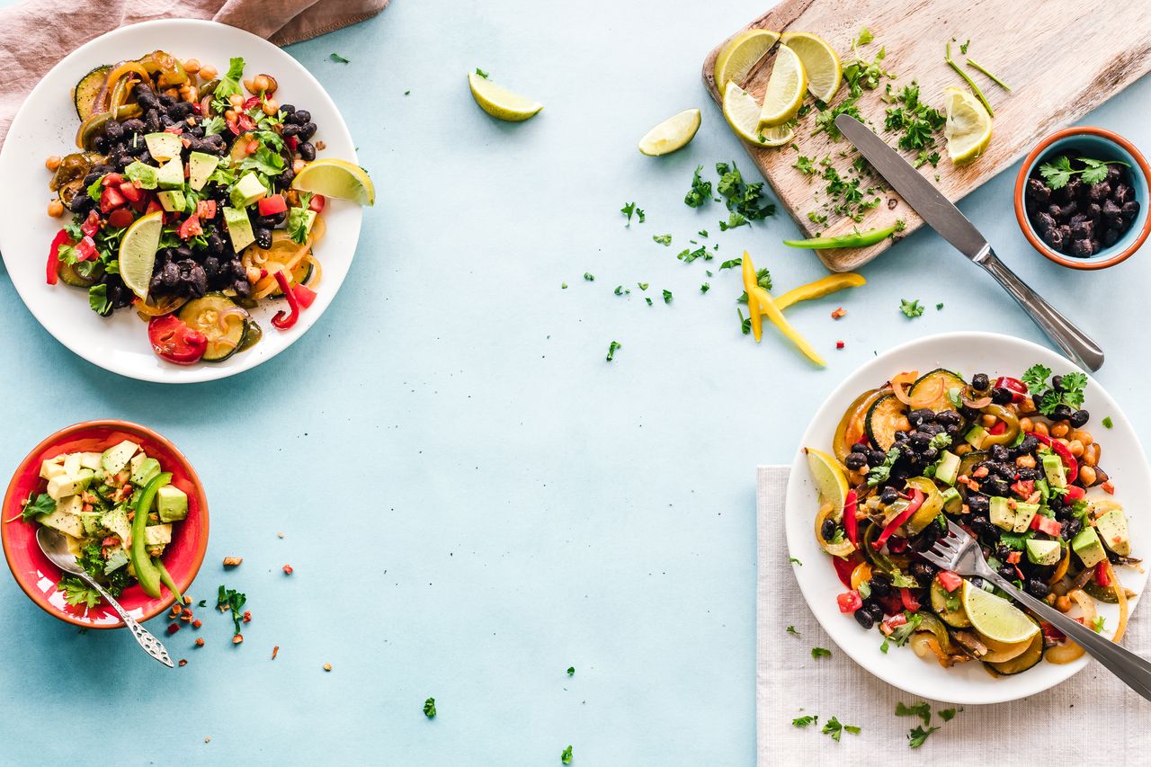 Home Colorful Mexican salad with avocado, black beans, and lime on a light blue surface.