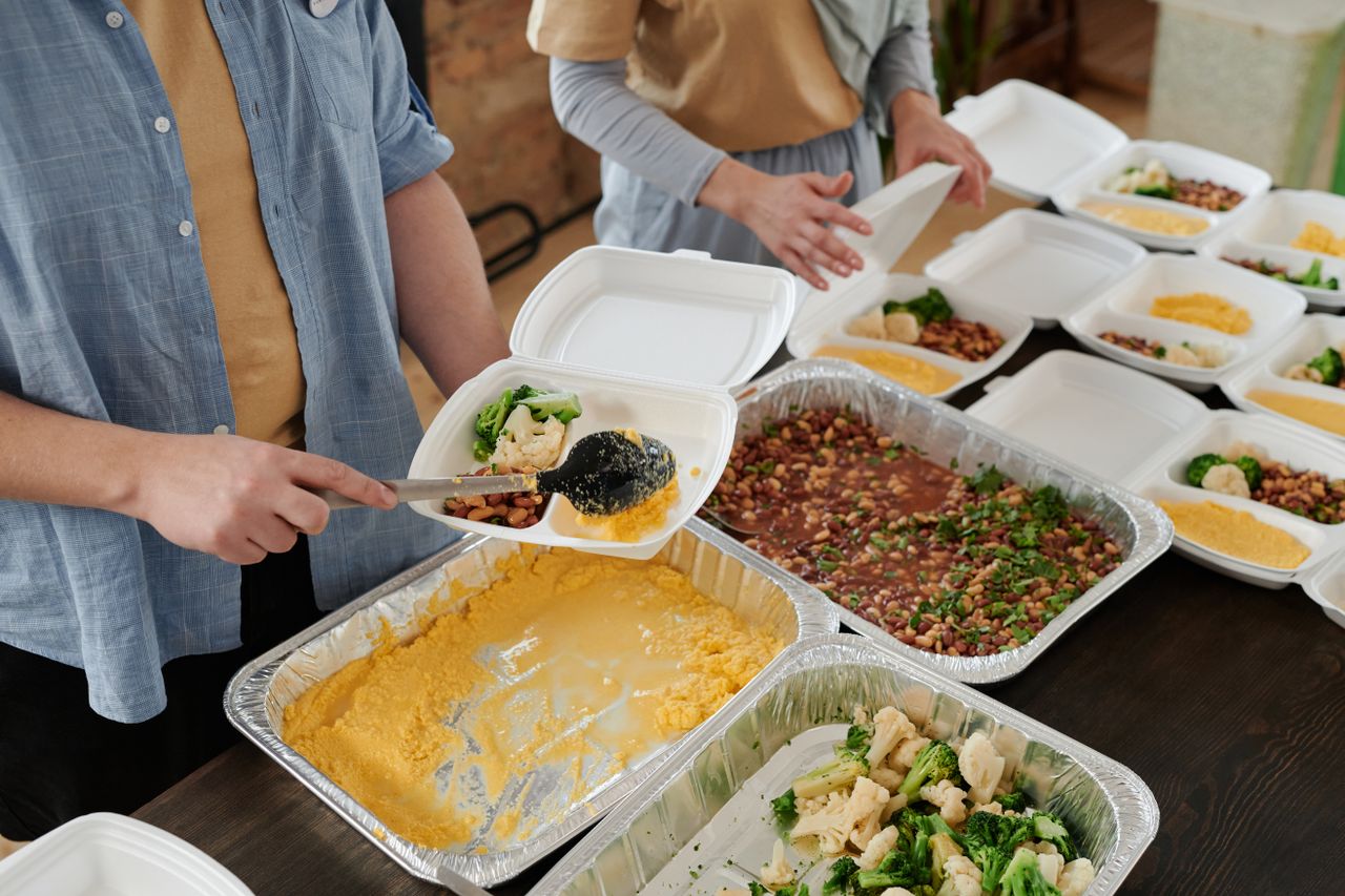 Volunteers preparing food packs indoors for donation.